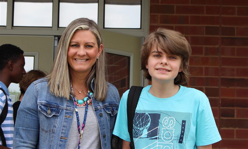 Two students smile in front of a school building